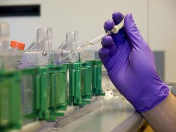 gloved hand pipetting into test tubes